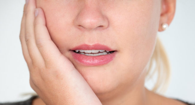 Frau, die sich die Wange hält